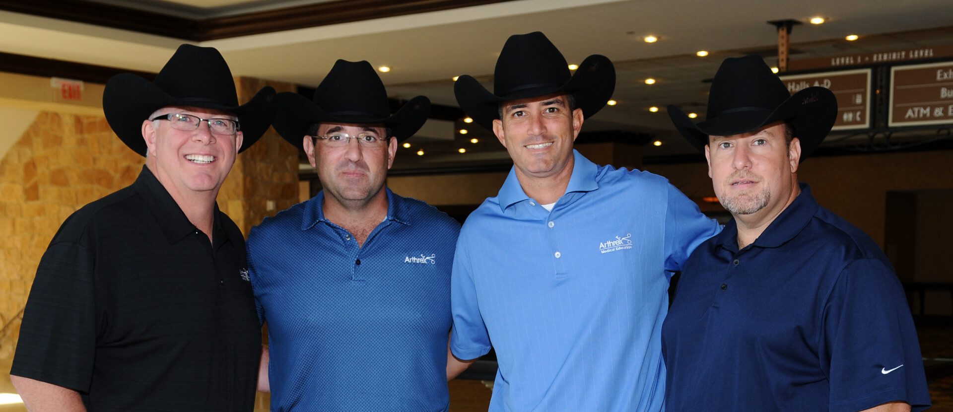 Two men wearing hats and blue shirts posing for a picture.