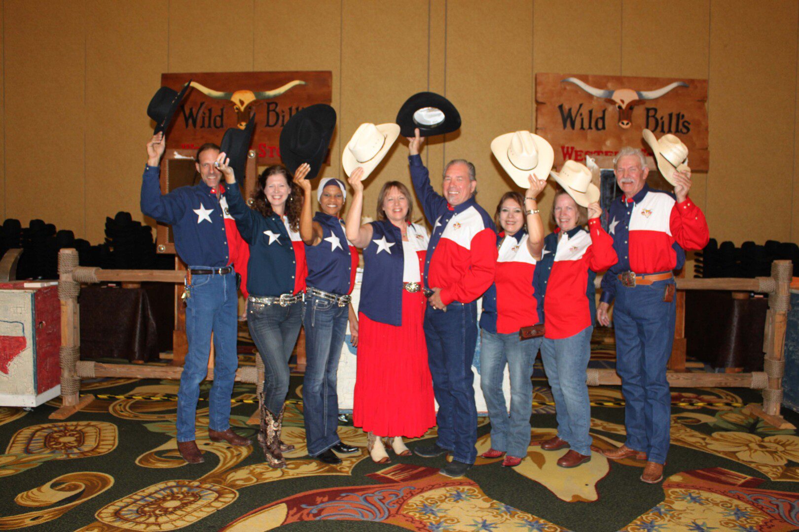 A group of people in red and blue shirts holding hats.