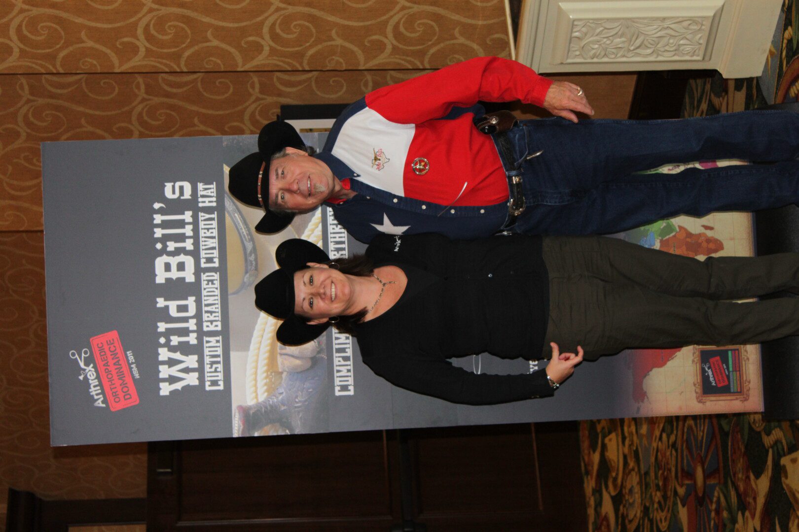 A man and woman posing for a picture in front of a sign.