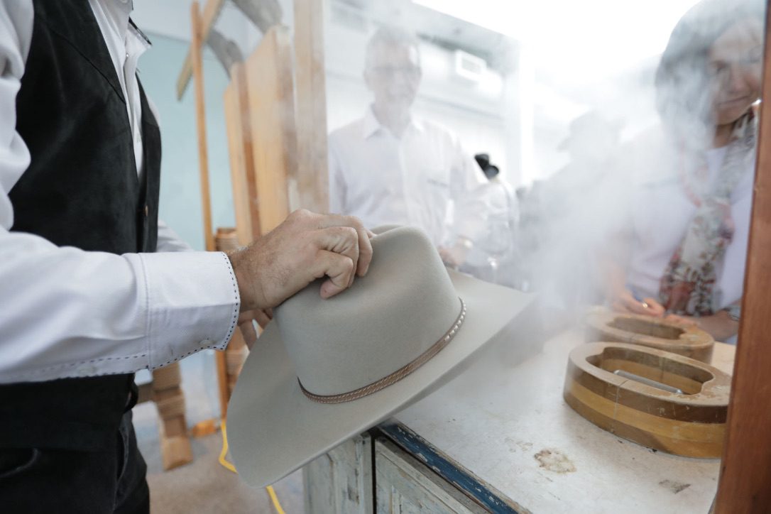 A man holding up a hat on top of a counter.