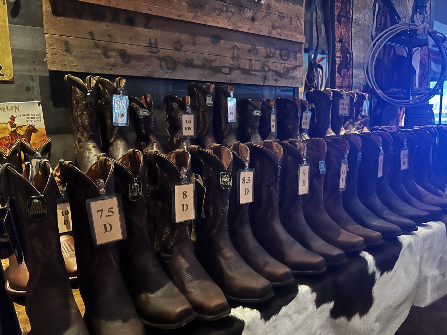 A row of cowboy boots with price tags on them.