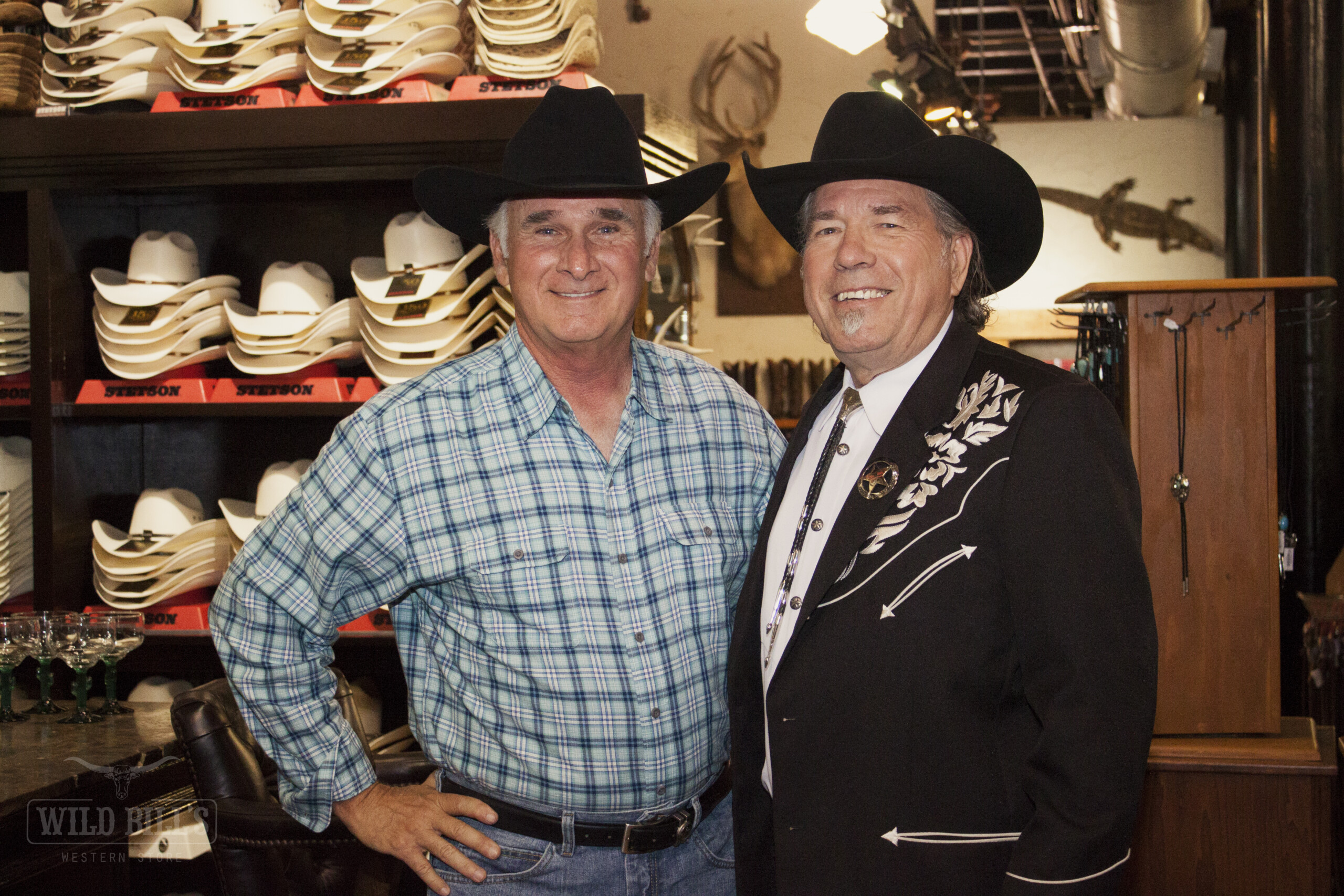Two men in cowboy hats and suits posing for a picture.